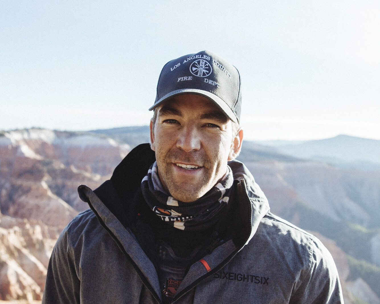 Sean Travis, operating founder, outdoors in his fire department cap with canyon country behind him.