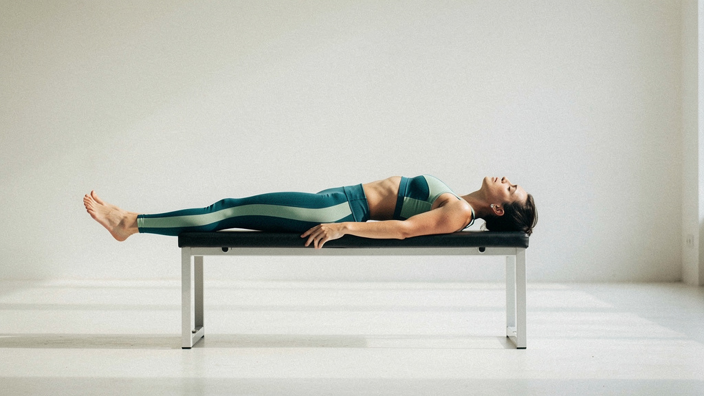 An athletic figure resting on a bench in clean daylight after effort, fully still.
