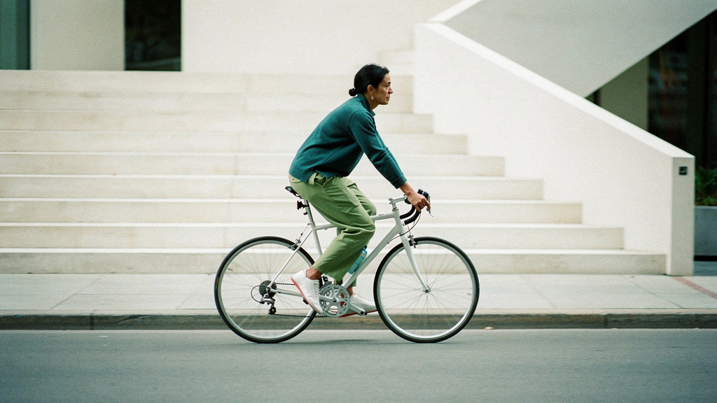 A person cycling briskly through a calm street in clean morning light.
