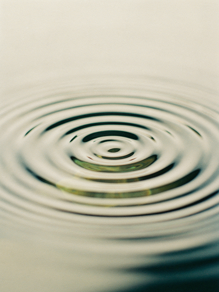 Gentle concentric ripples spreading across still water in clean light.