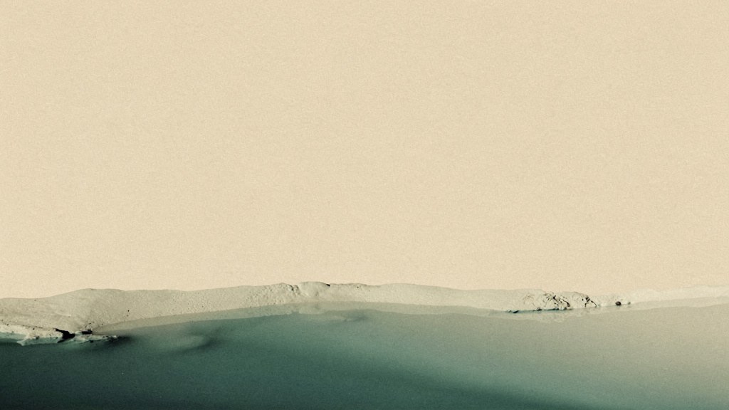 A low, settled reserve of soft matcha light pooled along the base of a warm bone field with wide open space above it, an abstract image of a mineral store quietly run down.