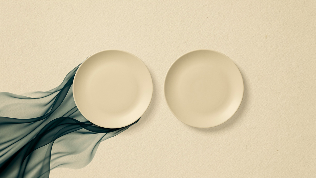 Two bone-colored plates hold the same weight of matched food, yet one empties into deeper teal while the other rests calm, the difference living in the making rather than the numbers.