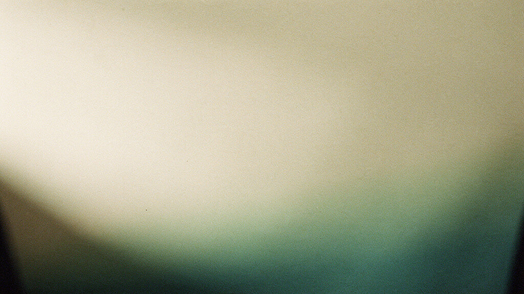 A calm bone-colored field warmed by a soft, low-angle diffuse glow that gathers into a quiet matcha-into-deep-teal gradient, an abstract image of light becoming something the body quietly holds.